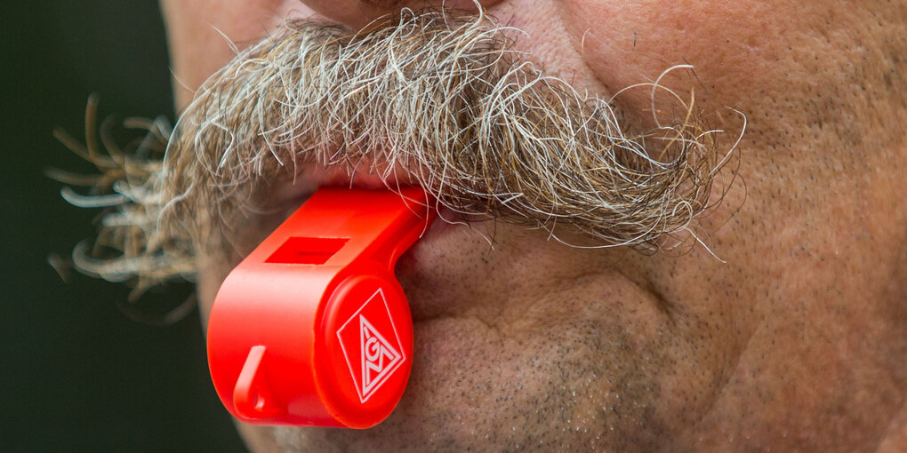 Ein Mann mit Schnaubart und Trillerpfeife zwischen den Lippen