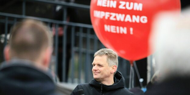 Martin Schwab mit Mikro in der Hand steht vor einem Luftballon: Nein zum Impfzwang nein