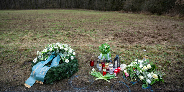 Ein Kranz, Blumen und Totenkerzne am Tatort, wo die Polizist*innen erschossen wurden