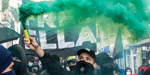 Eine grüne Pyrofahne, vermummte DemonstrantInnen, ein schwarzes Plakat "Free Ella"