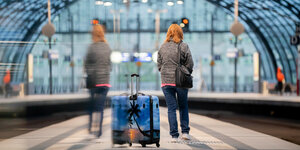 Frau mit Rollkoffer spoiegelt sich in einer Scheibe am Berliner Hauptbahnhof