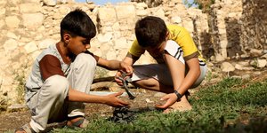 Kinder spielen nach einem Luftangriff mit Munitionsresten