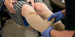 Ein alter Mann bekommt die Beine bandagiert