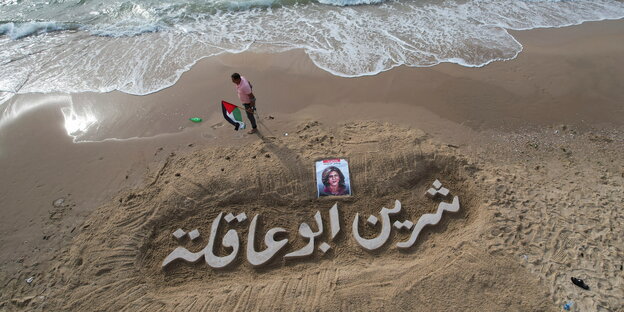 Eine Sandskulptur mit den namen Shireen Abu Skleh und einem Portrait der getöteten Journalisten am Strand von Gaza