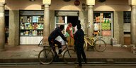 Straßenszene in Eritrea. Eine Frau steht vor einem kleinen Laden, ein junger Mann fährt mit dem Fahrrad vorbei