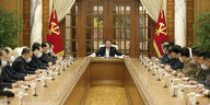 Kim Jong Un sitzt an einer langen Tafel mit Mitglieder der regierenden Arbeiterpartei