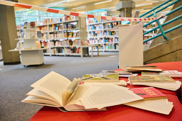 Zerschnittene und zerrissene Bücher liegen hinter Absperrband in einer Bibliothek