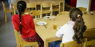 Zwei Kinder sitzen an einem Tisch und frühstücken