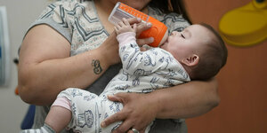 Ein Baby wird von seiner Mutter mit einer Flasch gefüttert