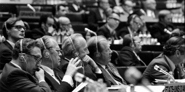 Männer sitzen mit Kopfhörern in einer Kongresshalle