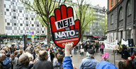 Mann hält rote Hand mit schwedischer Aufschrift Nein zum Nato-Beitritt hoch