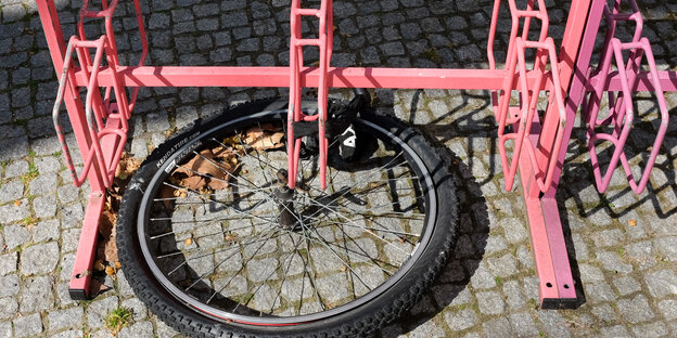 Ein einzelnes Fahrradrad hängt an einem Fahrradständer