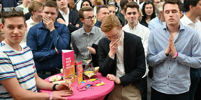 Enttäuschte junge Männer mit bestürzten Gesichtern an einem Stehtisch