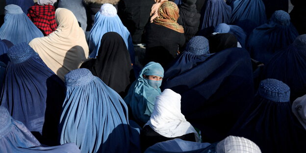 Ein Mädchen dreht sich um, sie sitzt in einer Gruppe Frauen, verschleiert und in Burkas