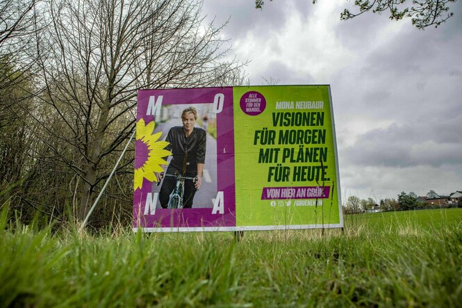 Wahlplakat von Mona Neubaur steht auf einer Wiese