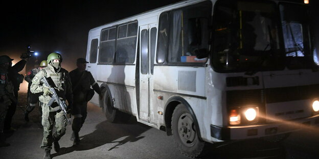 Ein Bus steht bei Nacht vor dem russischen Stahlwerk in Mariupol, Soldaten stehen daneben Ein Bus steht bei Nacht vor dem russischen Stahlwerk in Mariupol, Soldaten stehen daneben