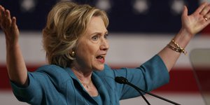 Hillary Clinton breitet an einem Rednerpult die Arme aus