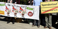 Menschen halten Transparente in der Hand, die gegen den Trauermarsch in Bad Nenndorf protestieren