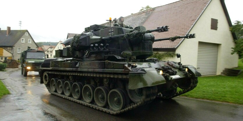 Ein Panzer fährt durch ein kleines Dorf