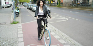 Das Foto zeigt die grüne Verkehrssenatorin Bettina Jarasch mit dem Rad auf einem Fahrradstreifen fahrend.