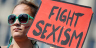 Eine Frau demonstiert gegen sexuelle Gewalt mit einem Transparent auf dem Fight Sexism steht