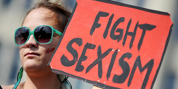 Eine Frau demonstiert gegen sexuelle Gewalt mit einem Transparent auf dem Fight Sexism steht