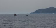 Blick auf das Meer, man sieht ein Schiff der griechischen Küstenwache und ein Flüchtlingsboot in der ferne