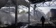 Silhouette eines Mann vor einer durch Bomben zerstörten Industrieanlage