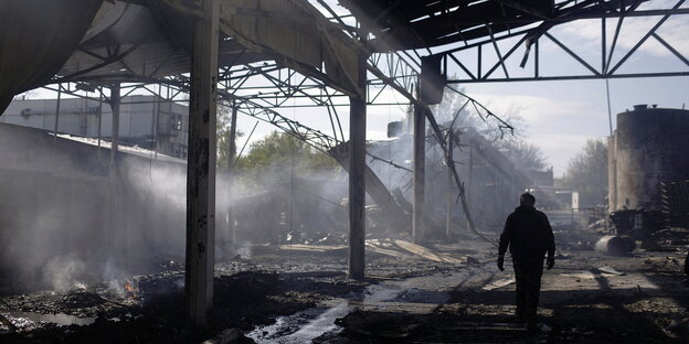 Silhouette eines Mann vor einer durch Bomben zerstörten Industrieanlage
