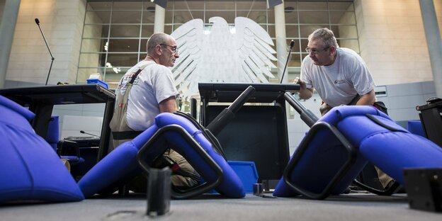 Arbeiter schrauben an den blauen Stühlen im Bundestag