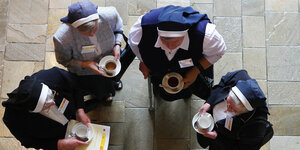Aufsicht auf vier blau gekleidete Nonnen, die Teetassen ind er Hand halten
