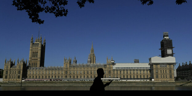 Ein Mensch läuft am Parlament Großbritanniens vorbei