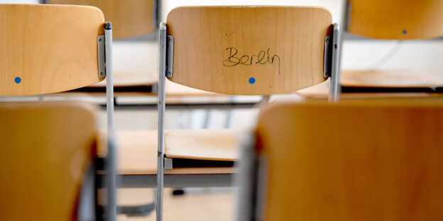 Stühle in einer Schulklasse, auf der Rückseite des einen hat jemand Berlin getaggt