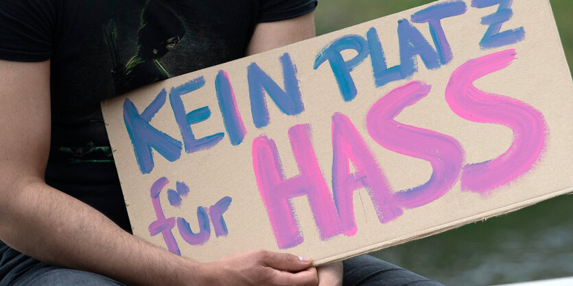 Ein Mann hält ein Schild "Kein Platz für Hass"