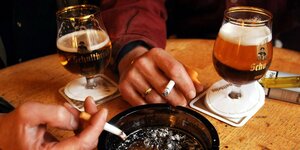 Kneipenbesucher trinken Bier und rauchen Zigaretten