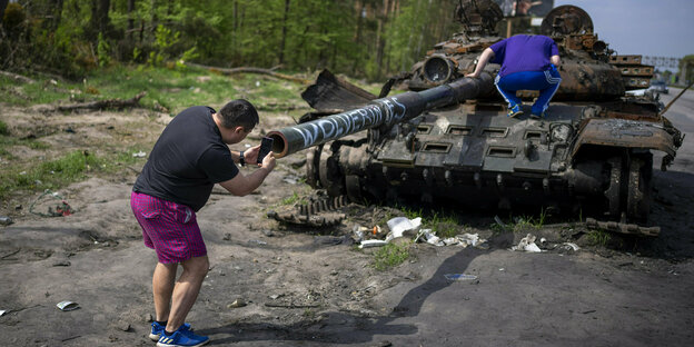 Ein Mann macht ein Foto eines zerstörten russischen Panzers bei Kiew