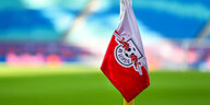 Eine Vereinsfahne von RB Leipzig, im Hintergrund unscharf Stadionrasen und -tribüne
