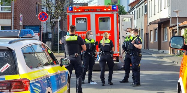 Polizisten, Streifenwagen und ein Krankenwagen stehen in der Nähe des Tatortes in der Burgdorfer Innenstadt.
