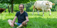Ulf Allhoff-Cramer, Landwirt, sitzt auf einer Weide neben einer von seinen Kühen. Der Bio-Bauer macht den Autokonzern VW mitverantwortlich für Schäden an seinem Hof.