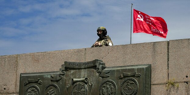 Russischer Soldat neben einer russischen Fahne an der Brüstung eines kriegerdenkmals