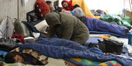 Flüchtlinge schlafen in Schlafsäcken auf dem Boden in einem Camp