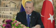 Der türkische Präsident Recep Tayyip Erdogan sitzend neben der türkischen Flagge