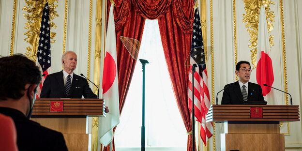 US-Präsident Joe Biden und Japans Premier Fumio Kishida vor Flaggen ihrer Staaten, im Vordergrund eine Journalistin von hinten.
