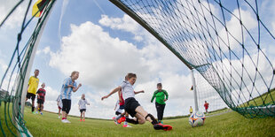 Kinder in bunten Trikots spielen Fußball