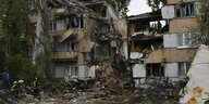 Rettungskräfte beseitigen die Schäden vor einem durch russischen Beschuss zerstörten Wohnhaus