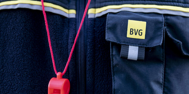 Ausschnitt einer BVG-Uniform mit Logo und roter Trillerpfeife