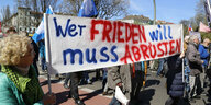 Beim Ostermarsch in Berlin halten DemonstrantInnen ein Plakat mit der Aufschrift "Wer Frieden will muss Aubrüsten"