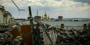 Zerstörte Dächer und im Hintergrund leuchten die goldenen Türme der orthodoxen Kirche