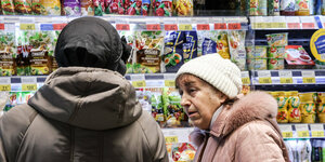 Zwei Frauen stehen vor einem Lebensmittelregal im Supermarkt. Alles Produkte sind kyrillisch beschriftet.