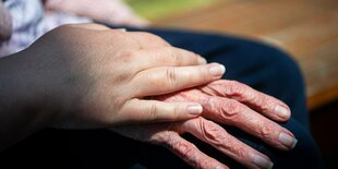 Die Hand einer jungen Person liegt auf der Hand einer alten Person